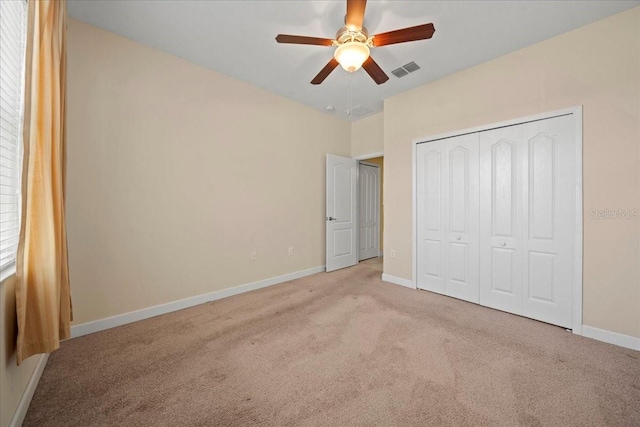 unfurnished bedroom with baseboards, visible vents, carpet, a closet, and ceiling fan
