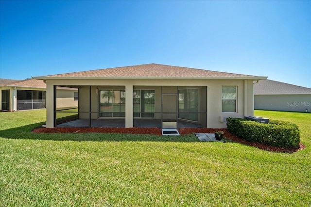 rear view of property with a sunroom, stucco siding, and a lawn