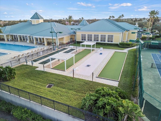 view of property's community with a swimming pool, a lawn, and fence