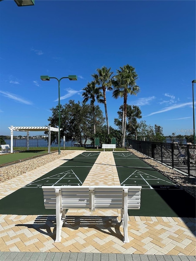 surrounding community with fence, a pergola, and shuffleboard