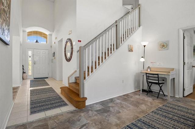 entrance foyer featuring baseboards, stairway, and a high ceiling