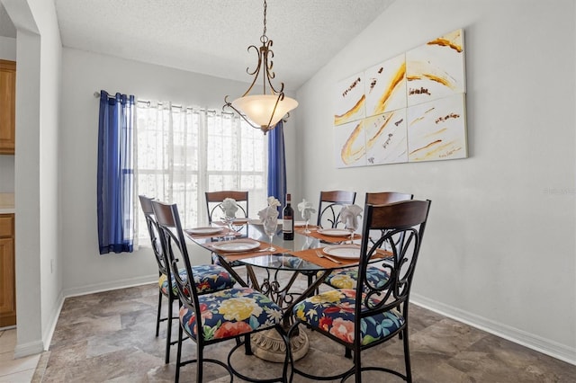 dining area featuring a textured ceiling, stone finish floor, and baseboards