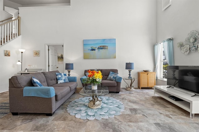 living area with visible vents, baseboards, a high ceiling, and stairs