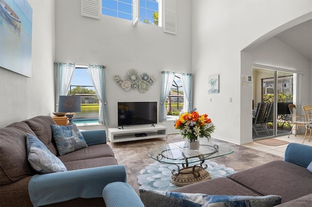 living area with arched walkways, a high ceiling, and a wealth of natural light