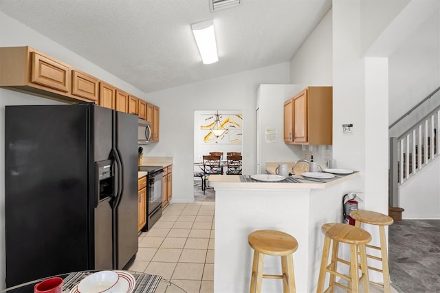 kitchen with a kitchen breakfast bar, a peninsula, light countertops, lofted ceiling, and black appliances