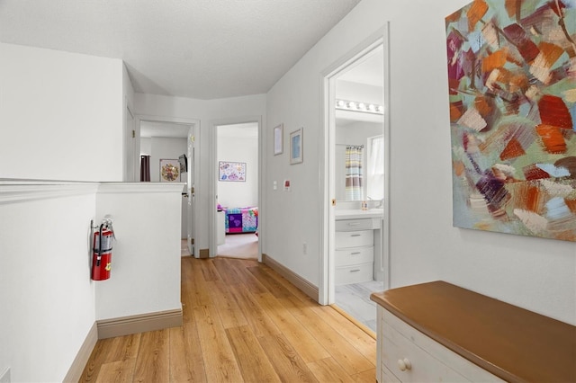 corridor featuring light wood-type flooring and baseboards
