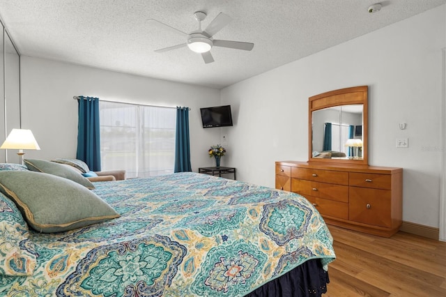 bedroom with light wood-style floors, ceiling fan, and a textured ceiling
