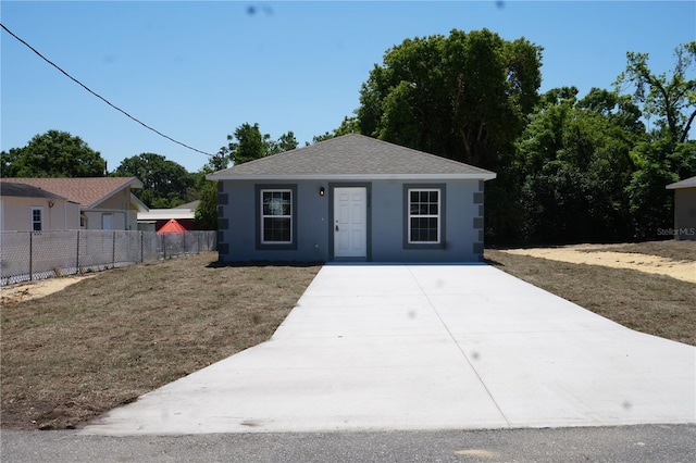 view of front of home with driveway, fence, a shingled roof, a front yard, and stucco siding