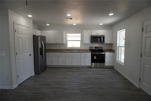 kitchen with white cabinets, baseboards, stainless steel appliances, and a sink
