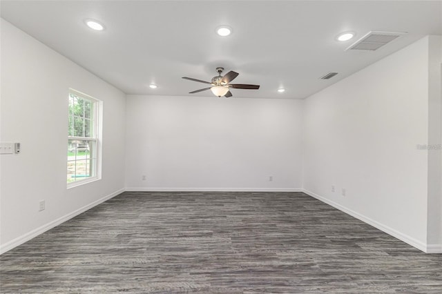 empty room featuring a ceiling fan, visible vents, and dark wood-style flooring