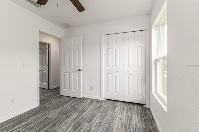 unfurnished bedroom featuring visible vents, baseboards, dark wood-type flooring, and multiple windows