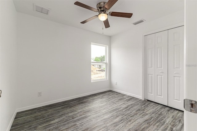 unfurnished bedroom with baseboards, wood finished floors, visible vents, and a closet