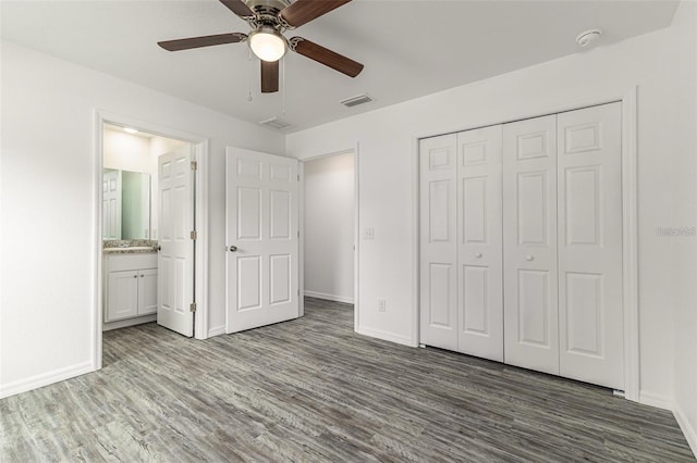 unfurnished bedroom with a closet, wood finished floors, visible vents, and baseboards