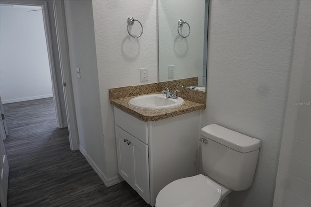 bathroom featuring baseboards, toilet, vanity, and wood finished floors