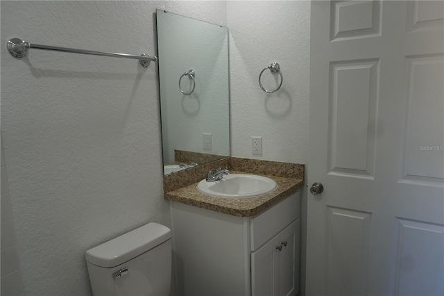 half bath featuring a textured wall, toilet, and vanity