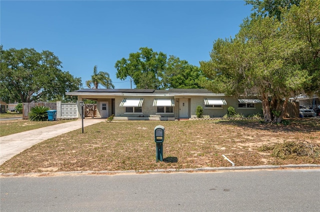 703 Osceola Ave, Lake Wales, FL 33853 - ranch-style house with fence, a front lawn, solar panels, driveway, and a carport