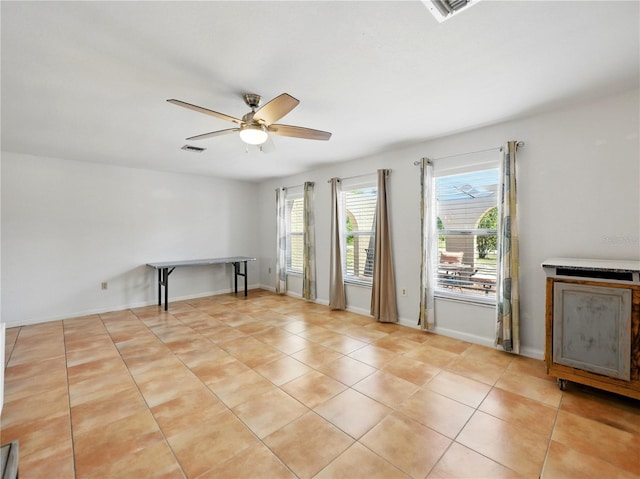 spare room with light tile patterned flooring, plenty of natural light, visible vents, and a ceiling fan
