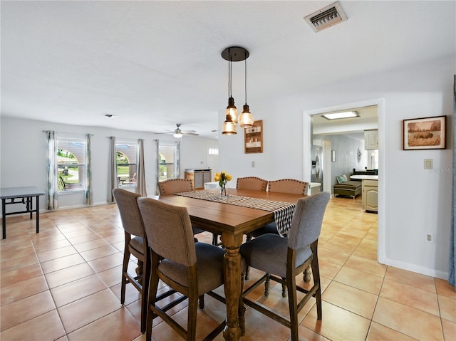 dining space featuring light tile patterned flooring, visible vents, a ceiling fan, and baseboards