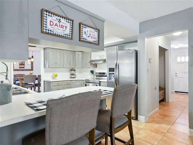 kitchen featuring a sink, gray cabinets, light countertops, a peninsula, and appliances with stainless steel finishes