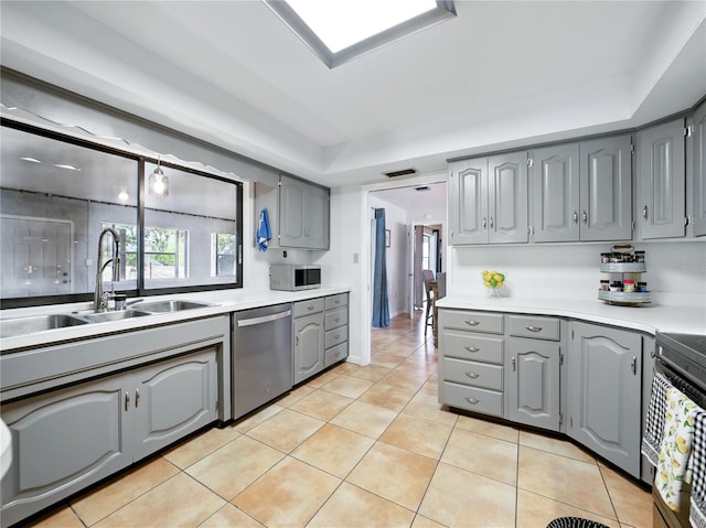 kitchen with stainless steel appliances, light countertops, gray cabinetry, and light tile patterned floors