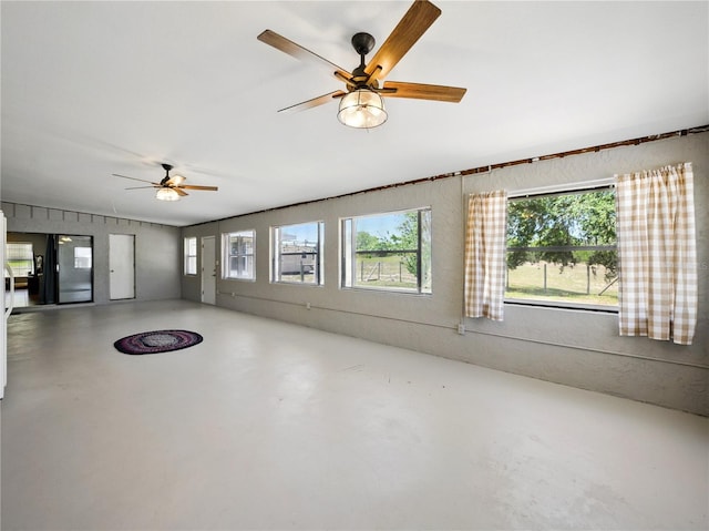 unfurnished living room featuring concrete floors, a ceiling fan, and plenty of natural light
