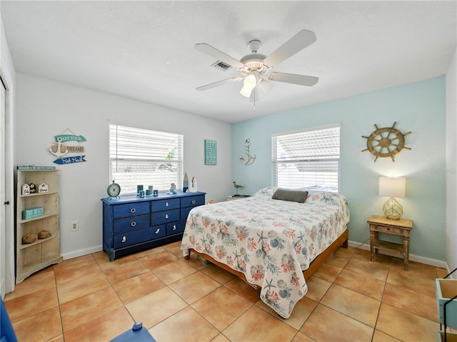 bedroom featuring a ceiling fan, visible vents, light tile patterned floors, and multiple windows