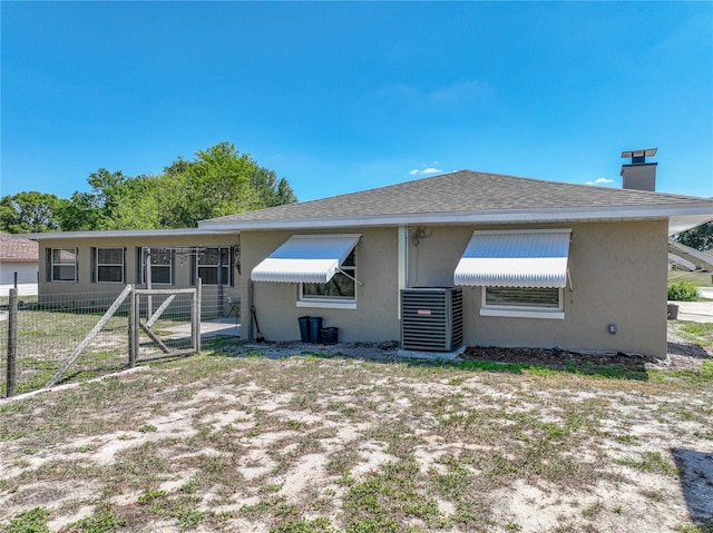 rear view of property with a gate, a chimney, fence, cooling unit, and stucco siding