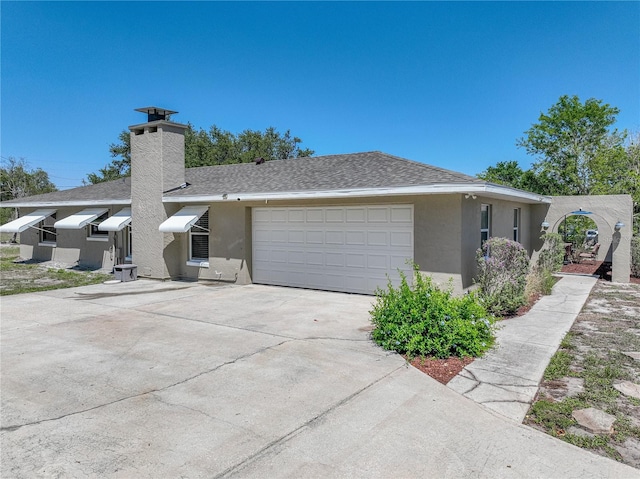 view of front facade with stucco siding, roof with shingles, and concrete driveway