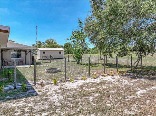 view of yard featuring an outdoor fire pit and fence