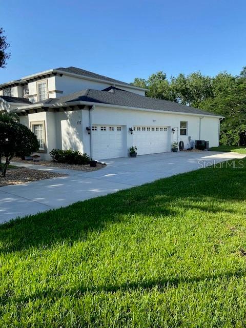 177 Costa Loop, Auburndale, FL 33823 - view of side of home with a garage, a lawn, stucco siding, and driveway