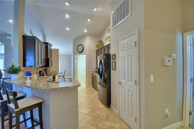 186 Viola Dr, Auburndale, FL 33823 - kitchen with freestanding refrigerator, a peninsula, a kitchen breakfast bar, light tile patterned flooring, and dark brown cabinetry