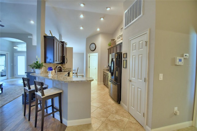 186 Viola Dr, Auburndale, FL 33823 - kitchen featuring freestanding refrigerator, a peninsula, a kitchen bar, light stone counters, and arched walkways