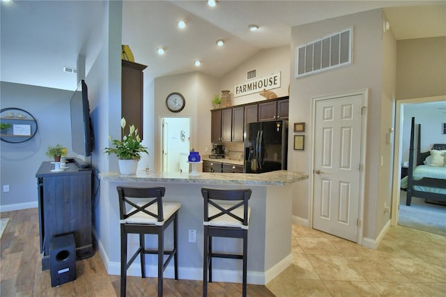 186 Viola Dr, Auburndale, FL 33823 - kitchen featuring black refrigerator with ice dispenser, a peninsula, a breakfast bar, dark brown cabinets, and high vaulted ceiling