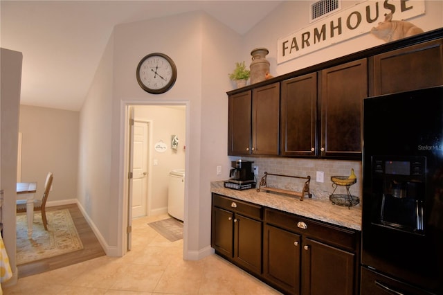 186 Viola Dr, Auburndale, FL 33823 - kitchen featuring black fridge, dark brown cabinets, vaulted ceiling, backsplash, and light stone counters