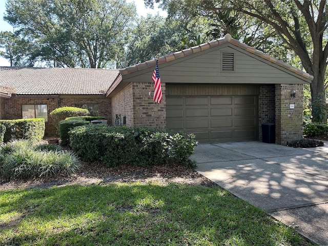 view of front of house featuring brick siding, a tiled roof, and driveway