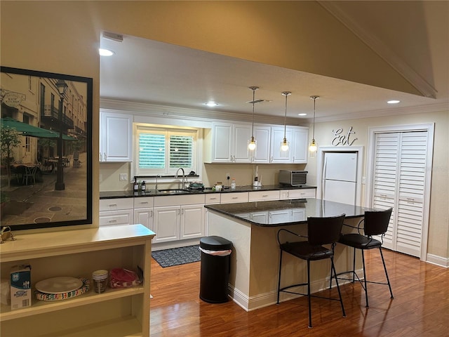 kitchen with white cabinets, freestanding refrigerator, and ornamental molding