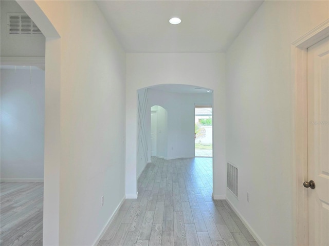 corridor featuring recessed lighting, light wood-type flooring, visible vents, baseboards, and arched walkways