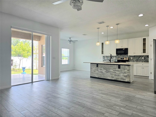 kitchen featuring visible vents, black microwave, a ceiling fan, and stainless steel range with electric cooktop