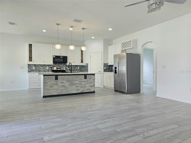 kitchen featuring tasteful backsplash, arched walkways, stainless steel appliances, visible vents, and a ceiling fan