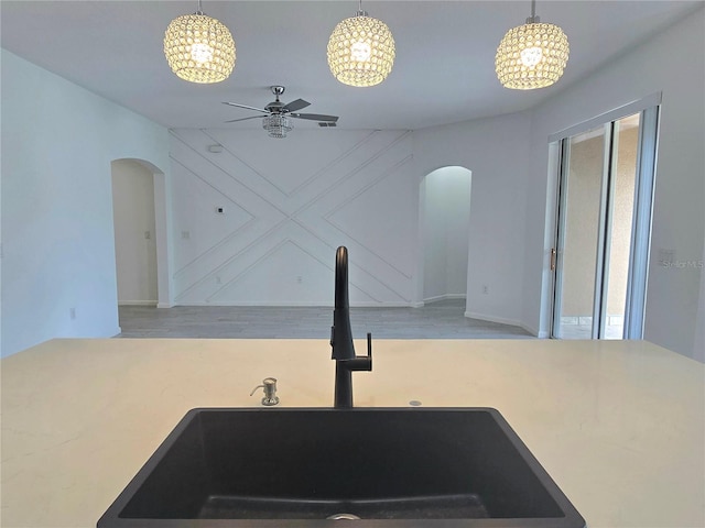 kitchen featuring arched walkways, a sink, wood finished floors, and pendant lighting