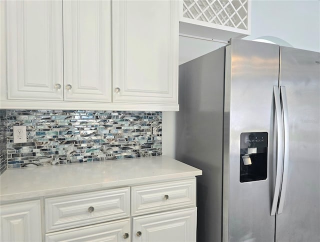 kitchen with stainless steel fridge, white cabinets, decorative backsplash, and light countertops