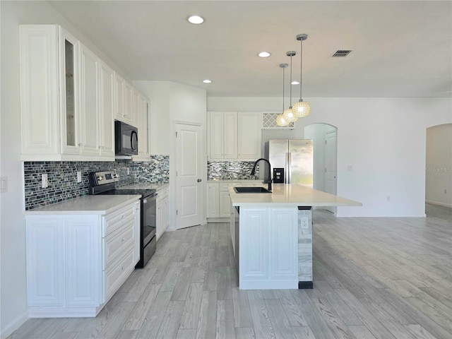 kitchen featuring a sink, stainless steel appliances, light countertops, and arched walkways