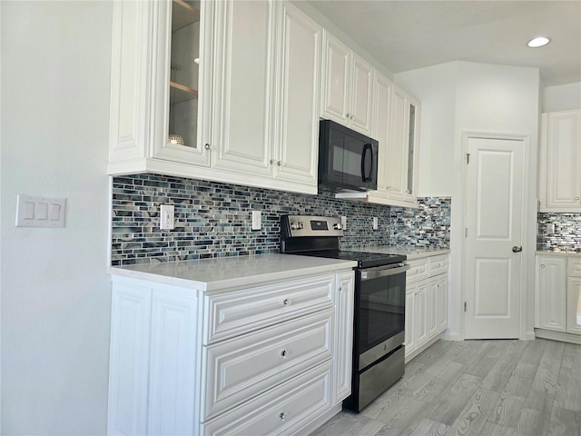 kitchen featuring decorative backsplash, stainless steel electric range oven, black microwave, light countertops, and white cabinets