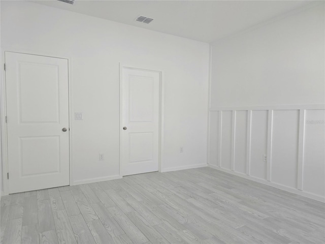 empty room featuring visible vents, light wood finished floors, and baseboards