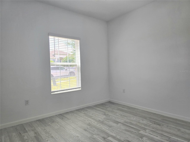 unfurnished room with baseboards and light wood-style floors