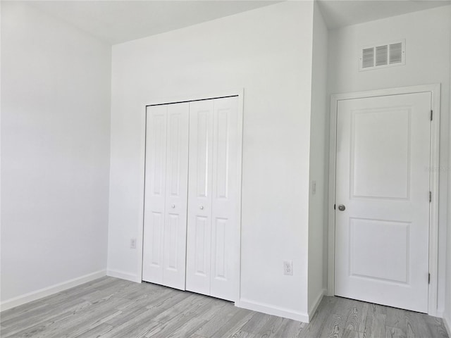 unfurnished bedroom with a closet, visible vents, baseboards, and light wood-type flooring