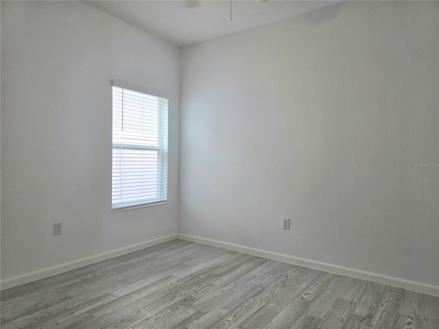 unfurnished room featuring baseboards, a wealth of natural light, and light wood-type flooring