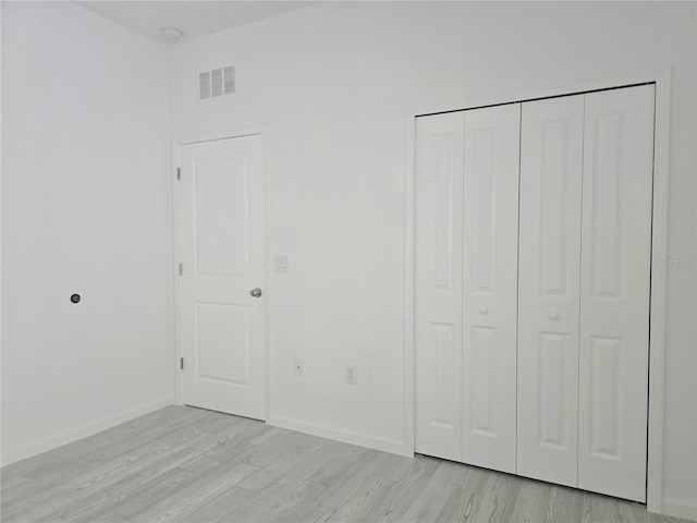 unfurnished bedroom featuring baseboards, visible vents, light wood-style floors, and a closet