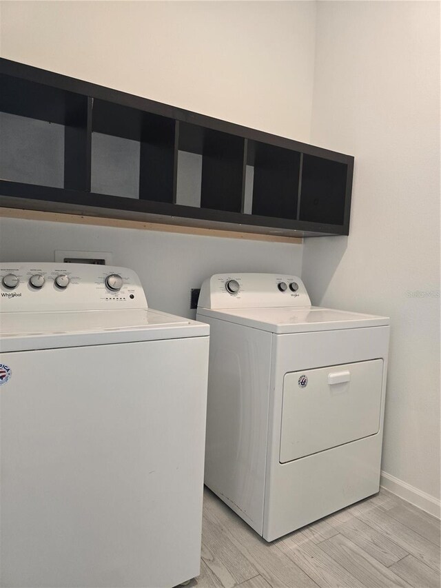laundry area featuring separate washer and dryer, baseboards, laundry area, and light wood-style floors