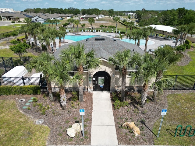 view of front facade featuring a community pool, fence private yard, and stucco siding